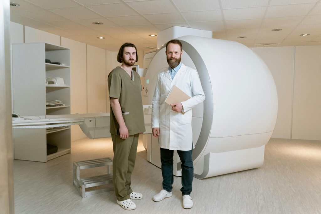 pexels-photo-7089386-7089386 Two doctors standing beside an MRI scanner in a modern medical facility.